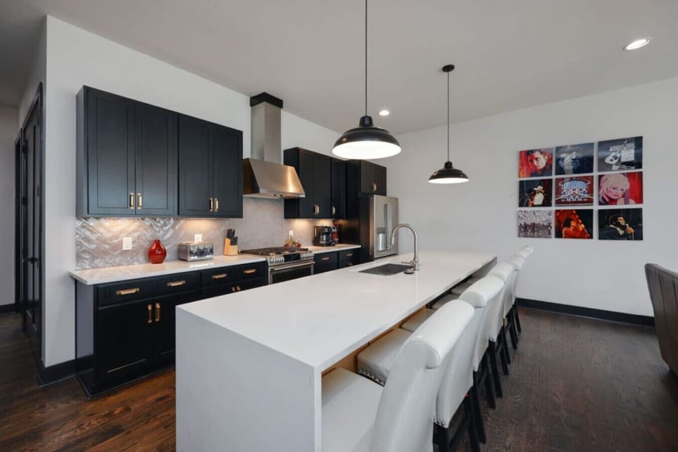 A sleek dark kitchen with a large island and pendant lighting.