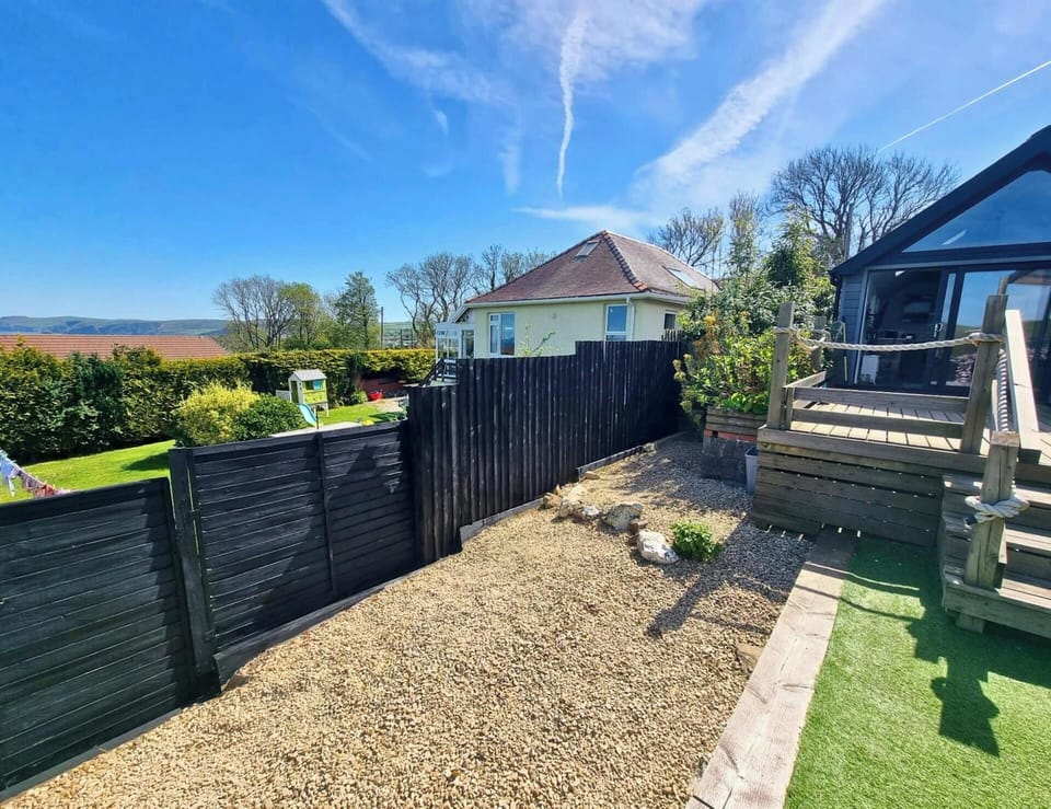 Black fence and gate beside a gravel yard, with wooden steps leading to a raised deck