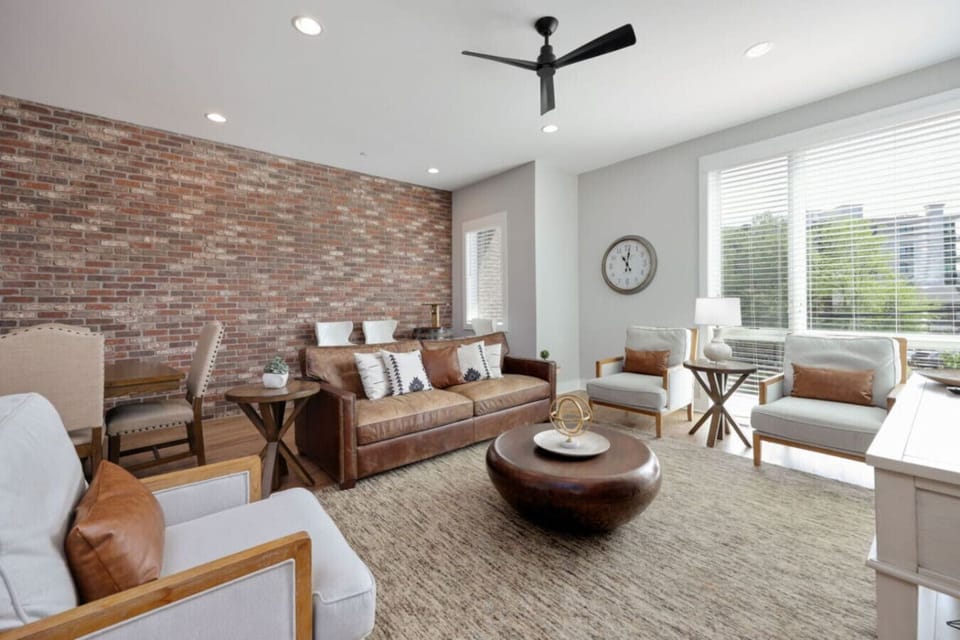 Open living and dining area with wooden beams, brick wall, and dining table visible