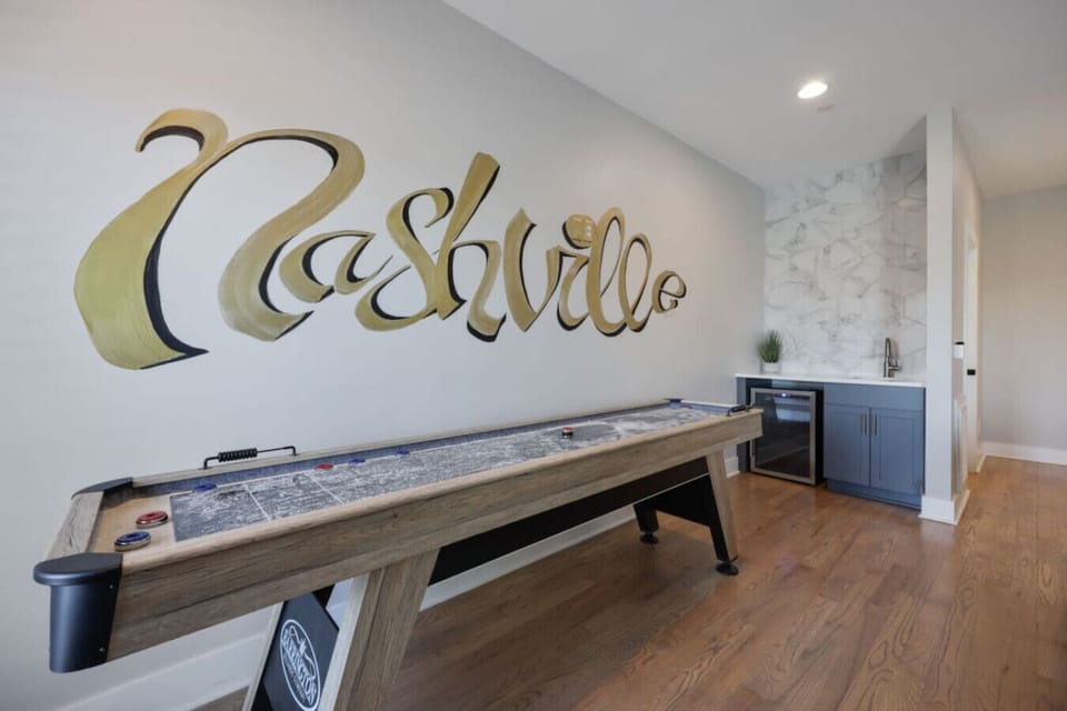 Game and entertainment room with long shuffleboard table and large Nashville script wall art
