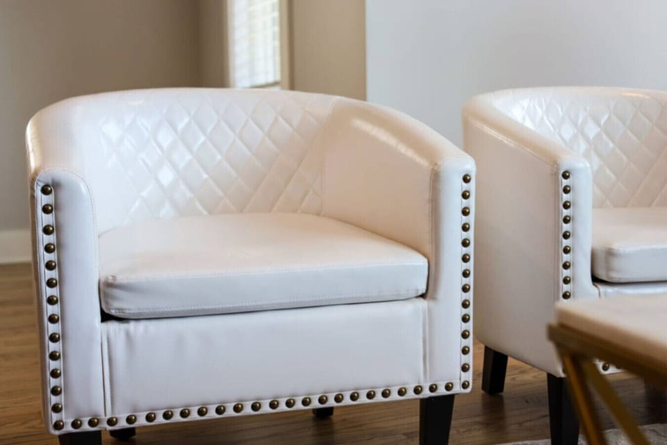 Close-up of white tufted barrel armchair with nailhead trim detail