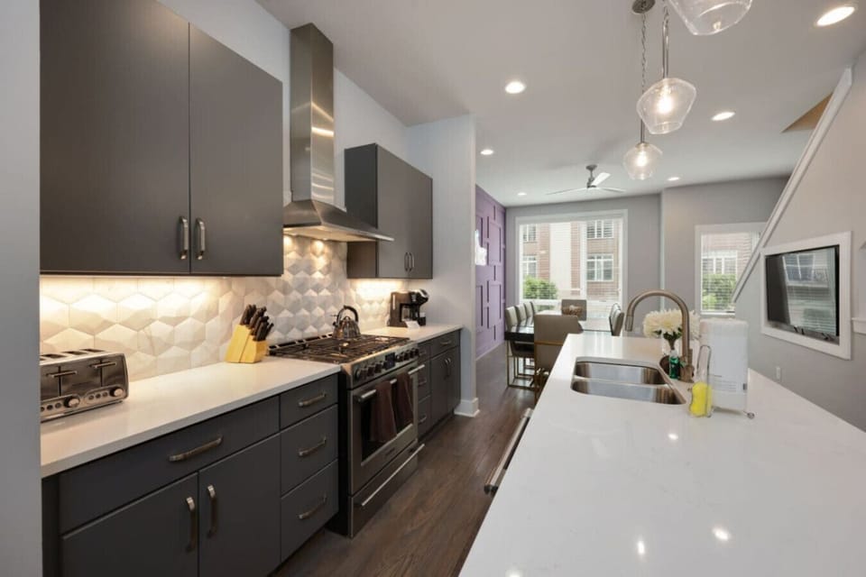 Kitchen with hexagonal tile backsplash, dark wood cabinetry, a gas range, and stainless appliances