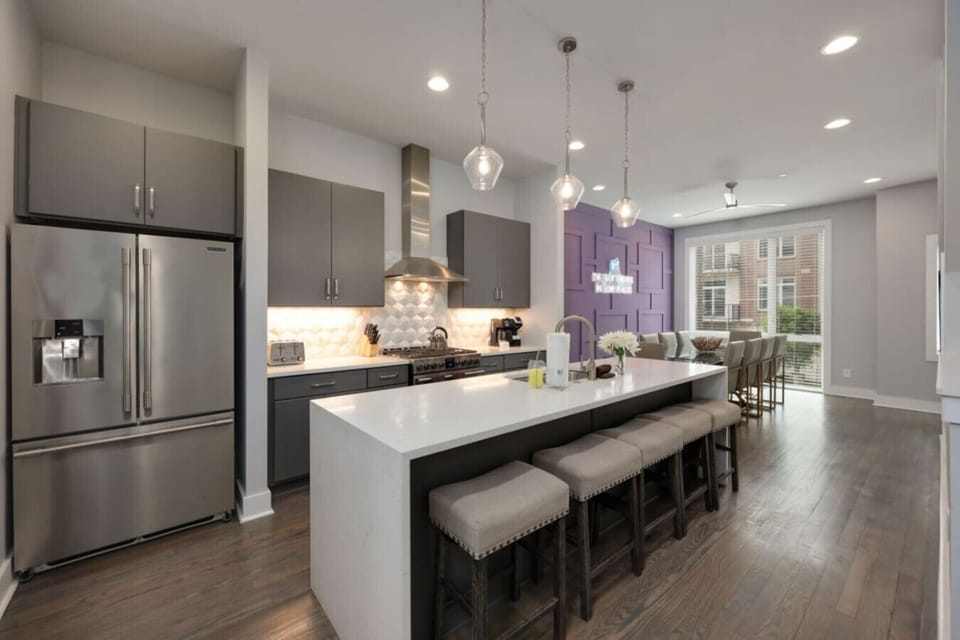 Kitchen with a large white island, stainless refrigerator, pendant lighting, and modern cabinetry