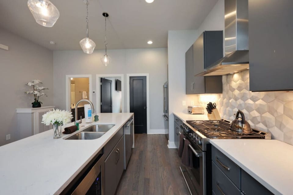 Kitchen island with white quartz counters, subway tile backsplash, a gas stove, and ample prep space
