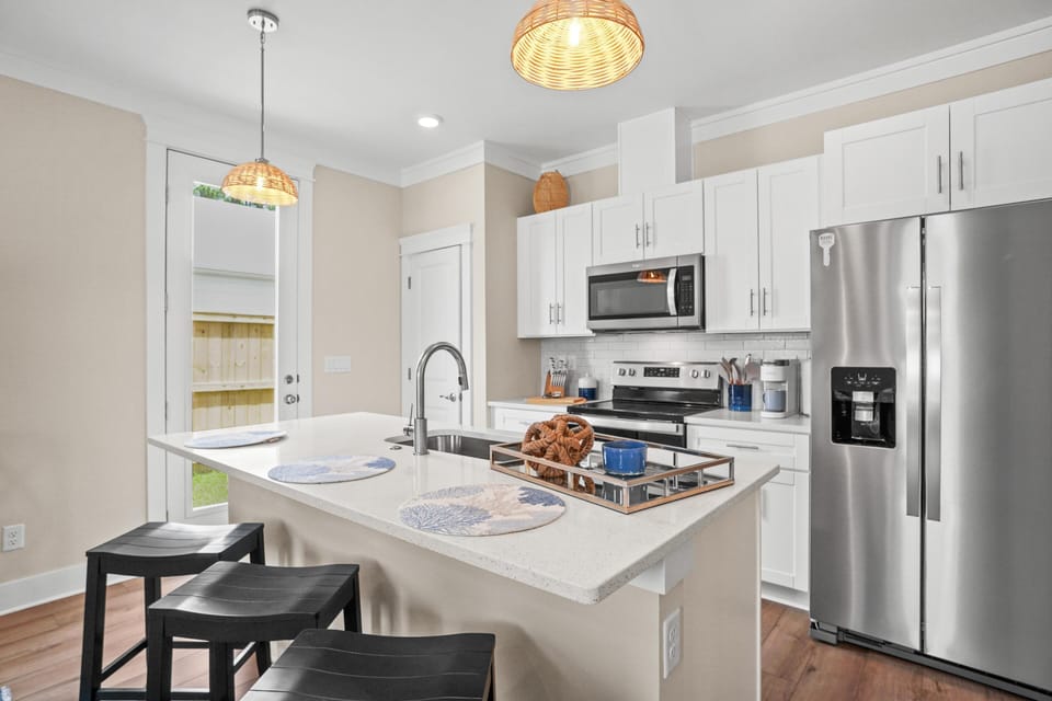 Your modern kitchen awaits with sleek granite counters, stainless appliances, and warm woven pendant lights creating the perfect space for culinary adventures.