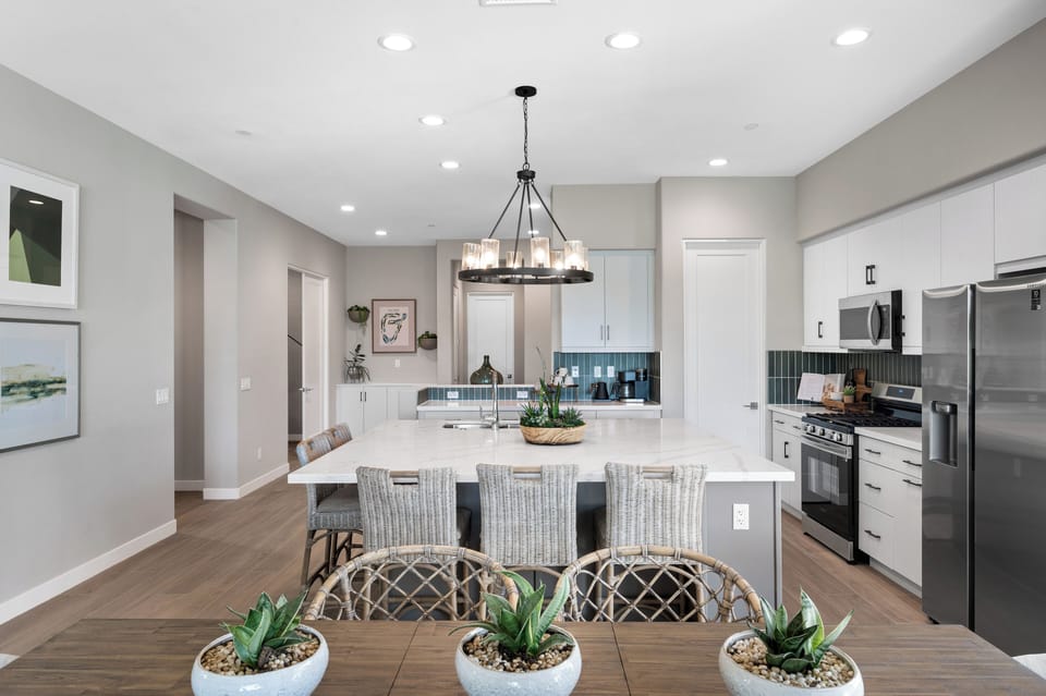 Dining table with a statement chandelier overhead and easy access to both kitchen and patio.
