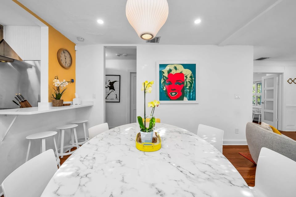 A bright, playful dining space with mid-century modern charm—featuring a marble tulip table, pop art accents, and a seamless flow into the vibrant living and kitchen areas.