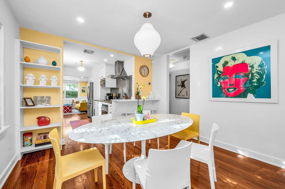 A bright, playful dining space with mid-century modern charm—featuring a marble tulip table, pop art accents, and a seamless flow into the vibrant living and kitchen areas.