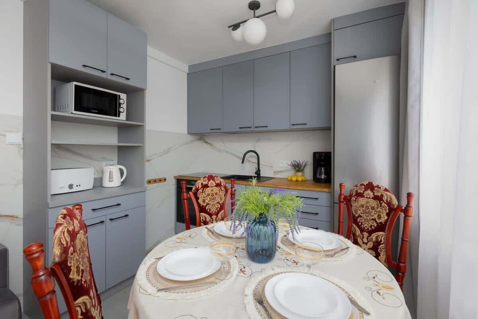 A compact kitchen area with grey cabinets and a dining table. Clean and functional design.