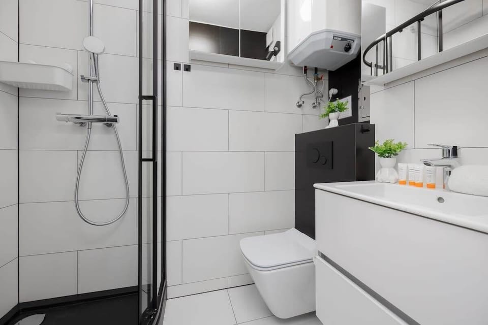 Another bathroom view with walk-in shower, toilet, and shelving. Clean design and easy to maintain.