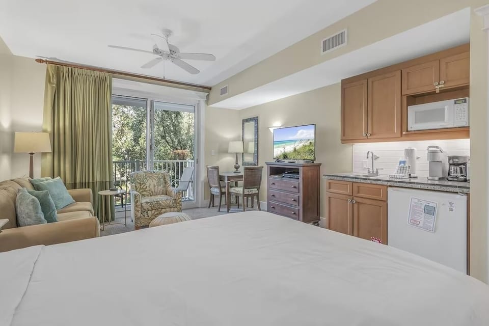 Spacious coastal studio with cozy bed, full kitchen, and balcony access—bright, airy, and perfect for relaxed beach living.