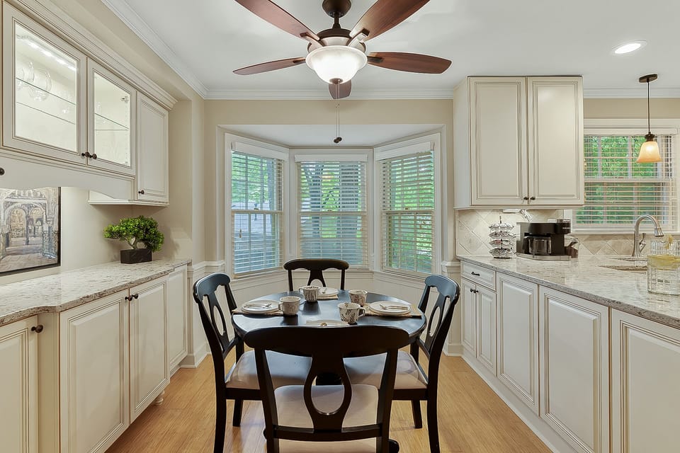 The kitchen dining area has a ceiling fan and windows with blinds