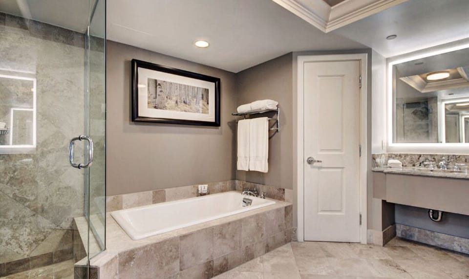 Relax and unwind in the luxurious bathroom featuring a spacious glass-enclosed shower and a separate soaking tub. The modern design is complemented by elegant fixtures and ample counter space, ensuring a spa-like experience.