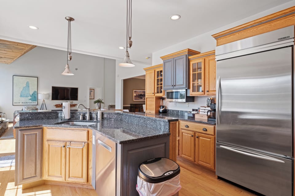 Bright kitchen with granite countertops, stainless steel appliances, and full kitchen equipment. Warm wood tones, cozy breakfast bar, and stylish pendant lighting for a welcoming vibe.