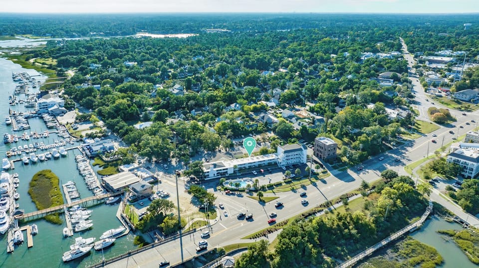 Aerial view of a coastal property nestled among lush greenery, with a marina, waterways, and nearby town amenities within easy reach.