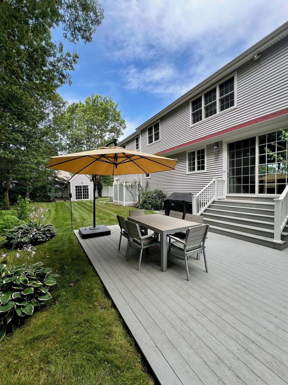 Side view of backyard with an outdoor Cape Cod style shower