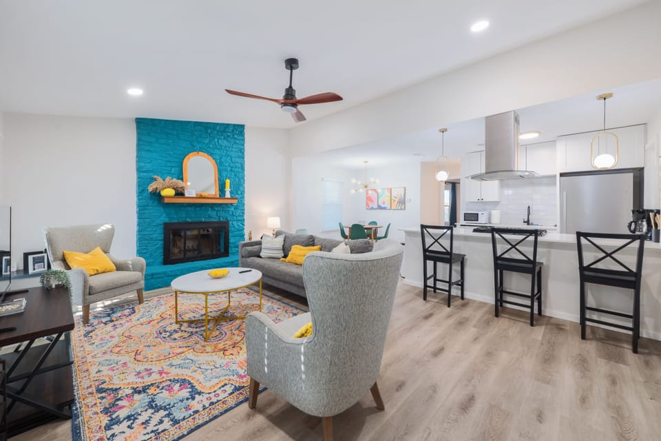 Relax in a spacious living room featuring a comfortable sofa, chairs, and mini table, all set beside a charming fireplace for a warm and inviting ambiance.