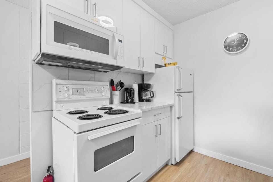 Bright kitchen setup with sleek white cabinetry, modern cooking appliances.