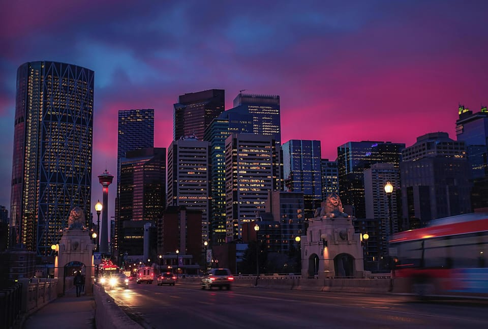 An artistic shot of Calgary’s city skyline bathed in purple sunset tones.