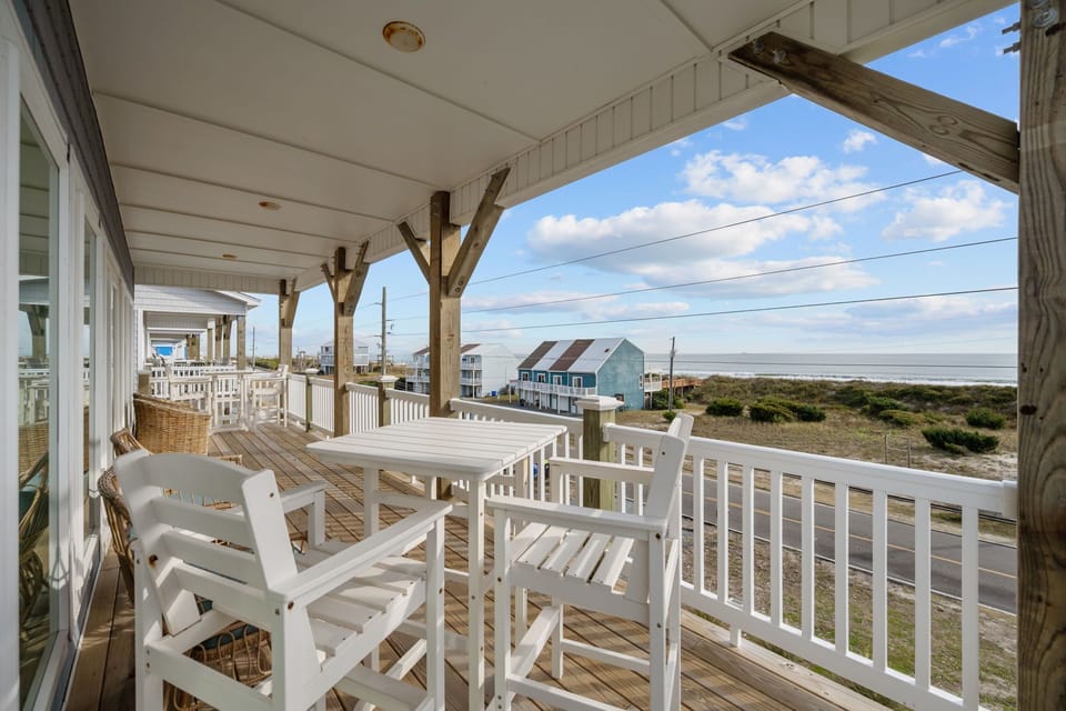 Spacious covered balcony with comfortable seating and direct beach access just steps away, perfect for enjoying ocean views and sea breezes.