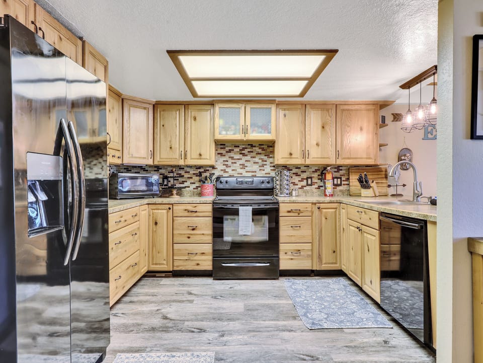 View of Kitchen Refrigerator, ample counter space, dishwasher, electric stove & oven, cooking spices, knife block, microwave, wood cabinetry, coffee maker
