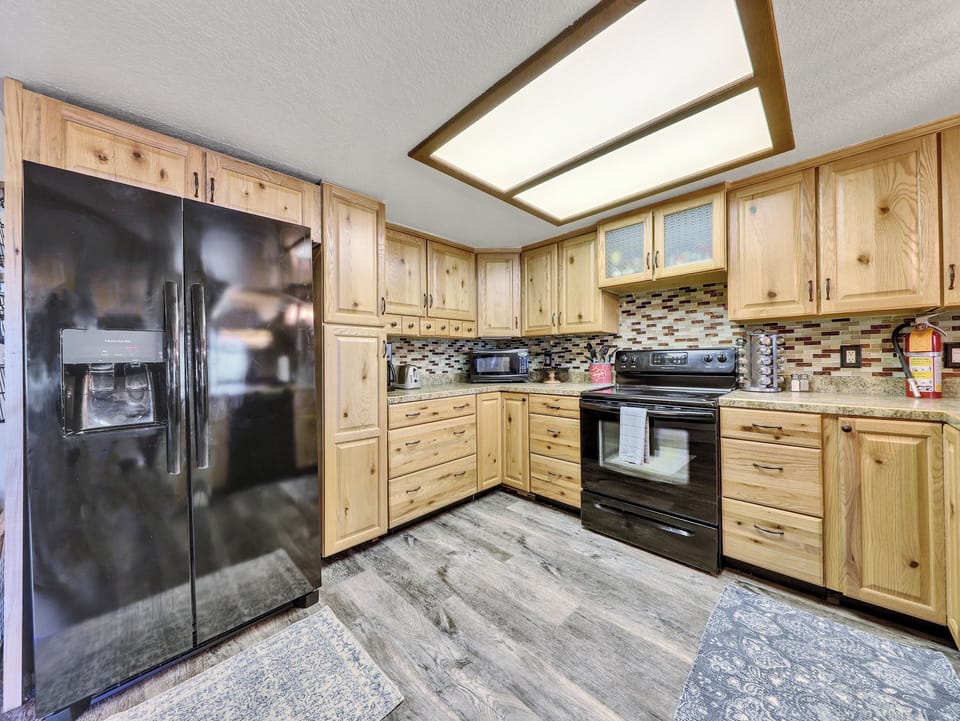Kitchen View, refrigerator, ample counter space, dishwasher, electric stove & oven, cooking spices, knife block, microwave, wood cabinetry, coffee maker