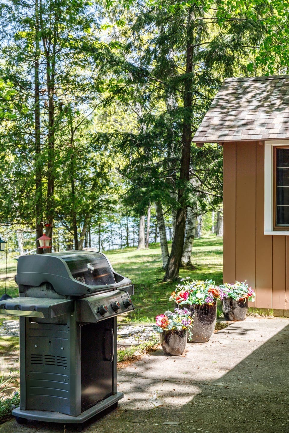 Outdoor grill ready for cookouts, set in a shady yard near the cabin.