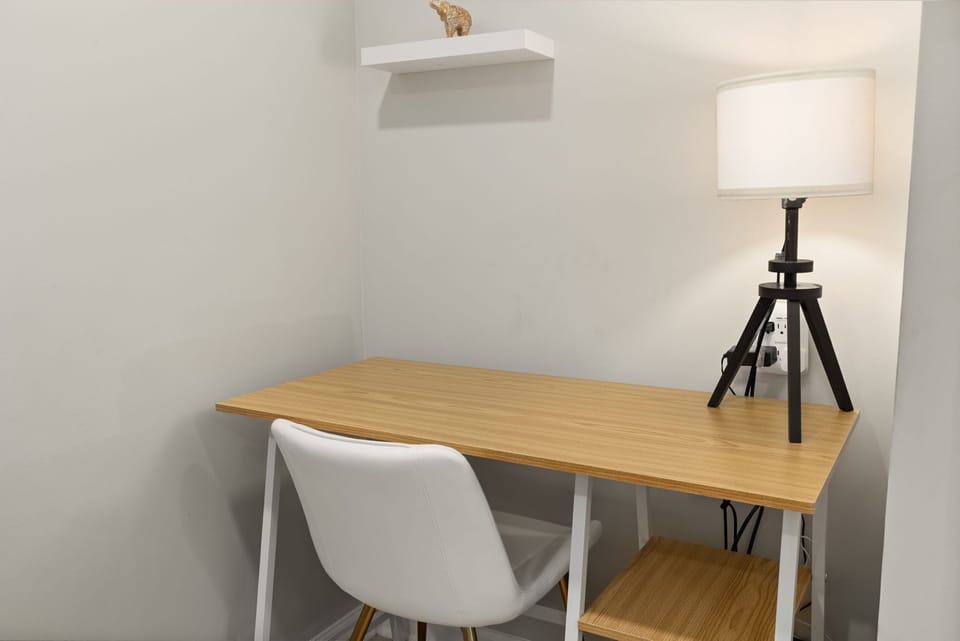 Minimalist work nook with desk, chair, and warm lamp lighting