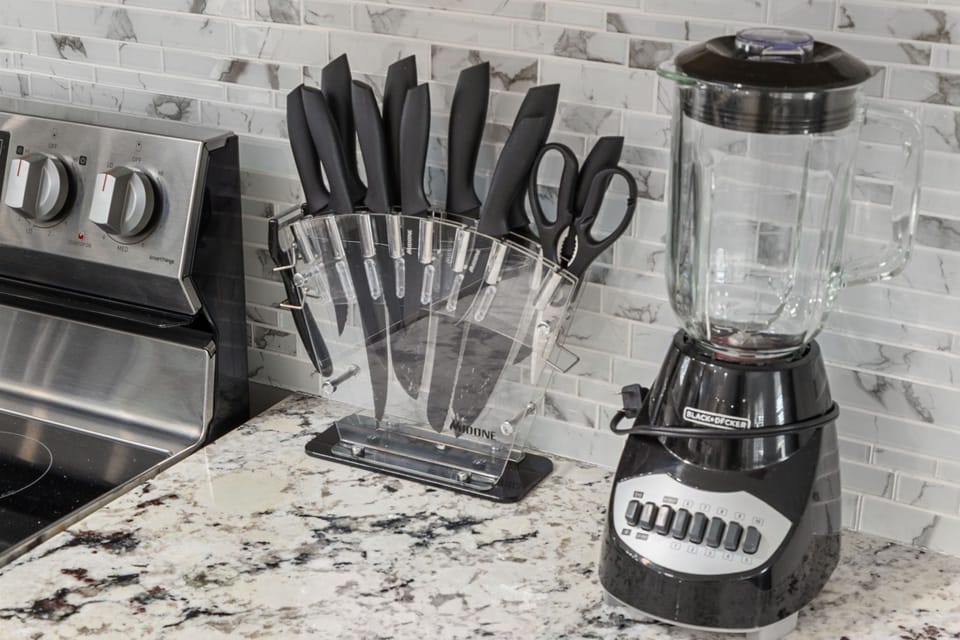 Modern kitchen with granite counters, blender, and full knife set
