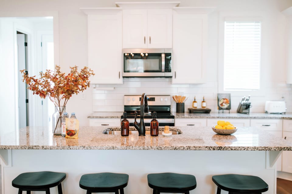 The kitchen island features four black barstools neatly tucked underneath, creating a modern, functional space perfect for casual dining and socializing.