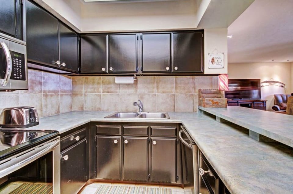 Prepare meals and entertain guests in the sleek kitchen, featuring dark wood cabinetry, granite countertops, and a convenient bar seating area for casual dining or socializing