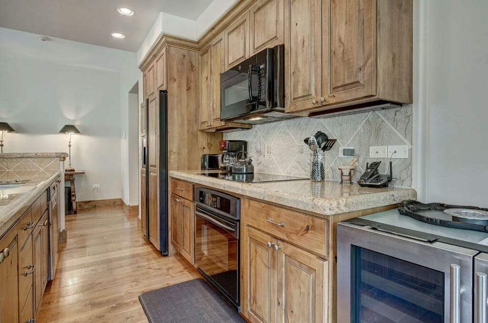 The kitchen comes complete with stainless steel appliances, wooden cabinetry, and a cozy fireplace, blending functionality with comfort.