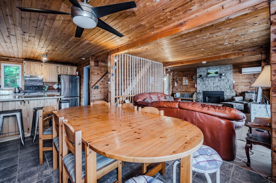 Enjoy family meals in this charming open-plan dining and kitchen area, featuring warm wooden furniture and modern conveniences, all set against the backdrop of serene lake views.