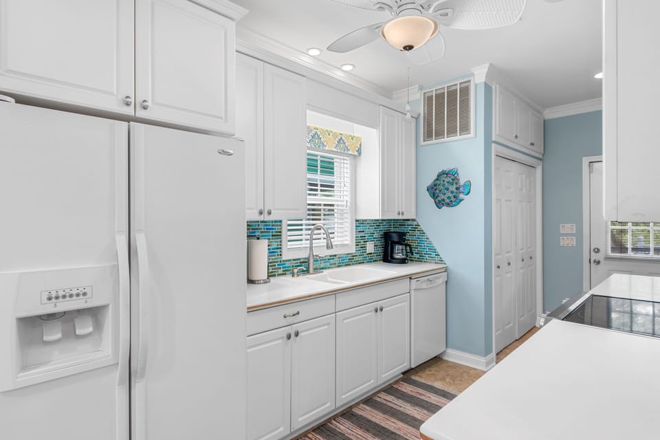 Step into your coastal-inspired kitchen with crisp white cabinets and cheerful turquoise accents that make cooking feel like a beach vacation.