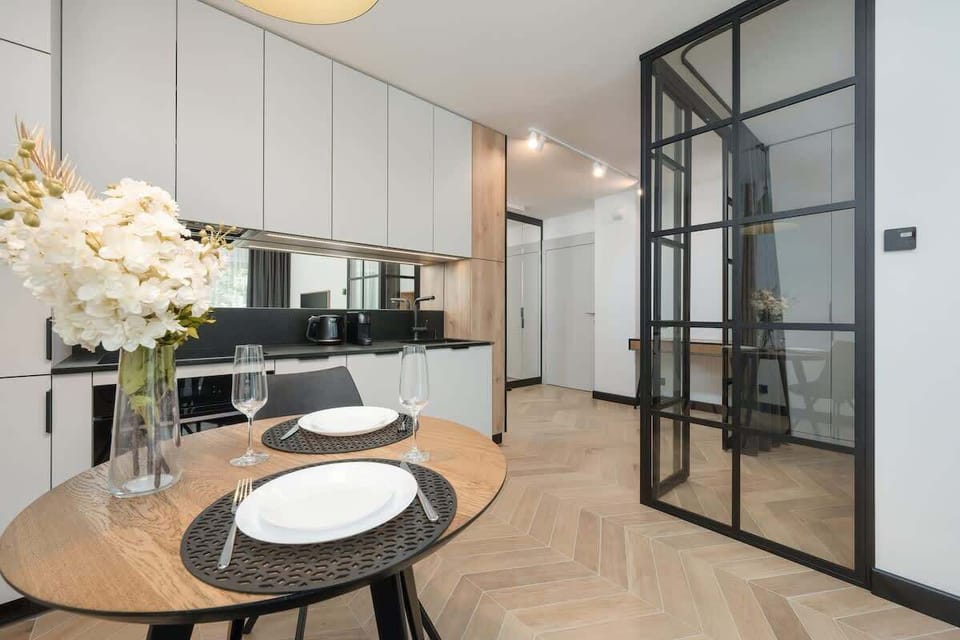 Another angle of a stylish kitchen and dining setup with a contemporary design. Features built-in cabinetry and a clean finish.