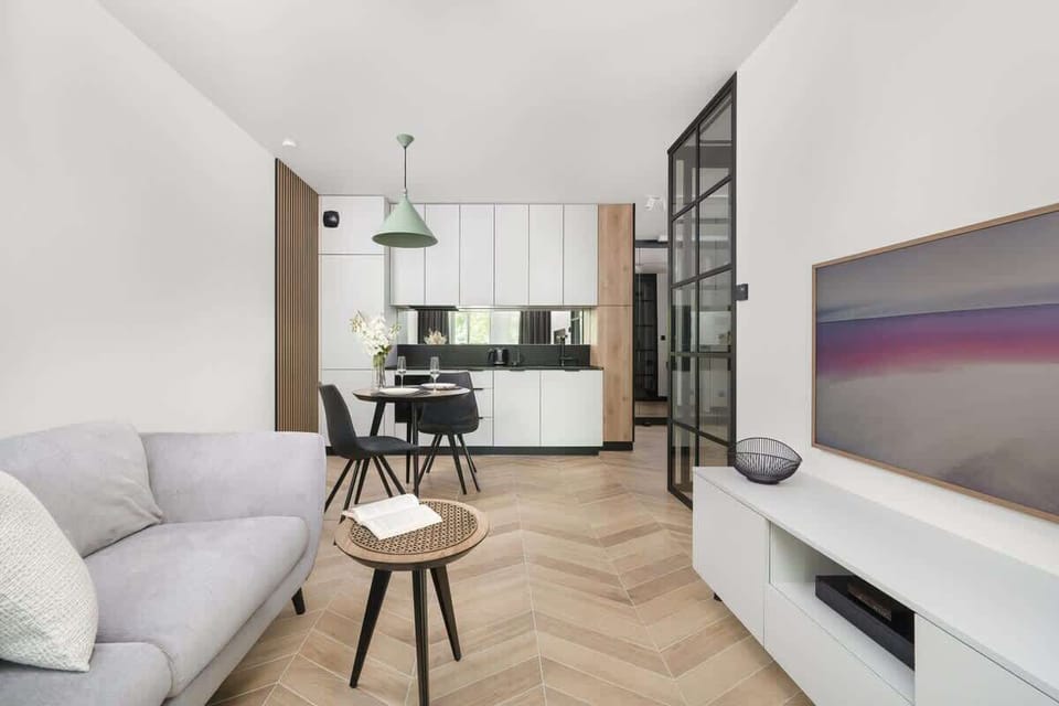 A contemporary open-plan living space with a grey couch and entertainment unit. Large windows enhance the spacious feel.