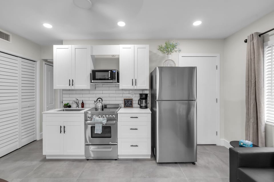 The full kitchen includes a coffee maker, kettle, microwave, fridge with freezer, and a 4-burner stove with oven, plus all essentials for cooking.