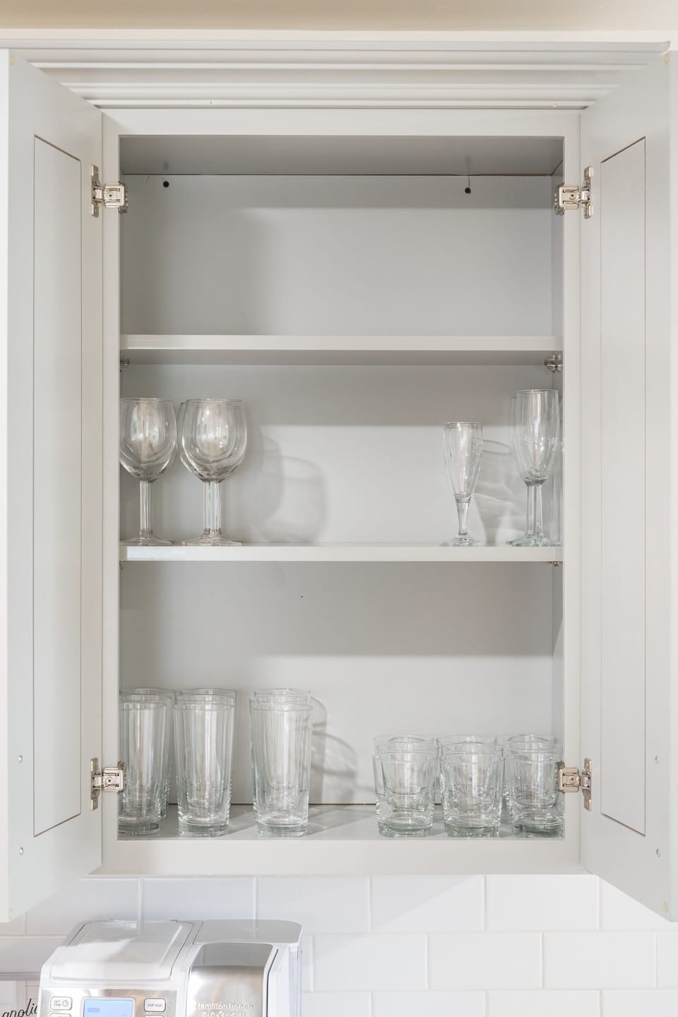 Well-stocked kitchen cabinet with glassware, mugs, bowls, and essentials for your stay.