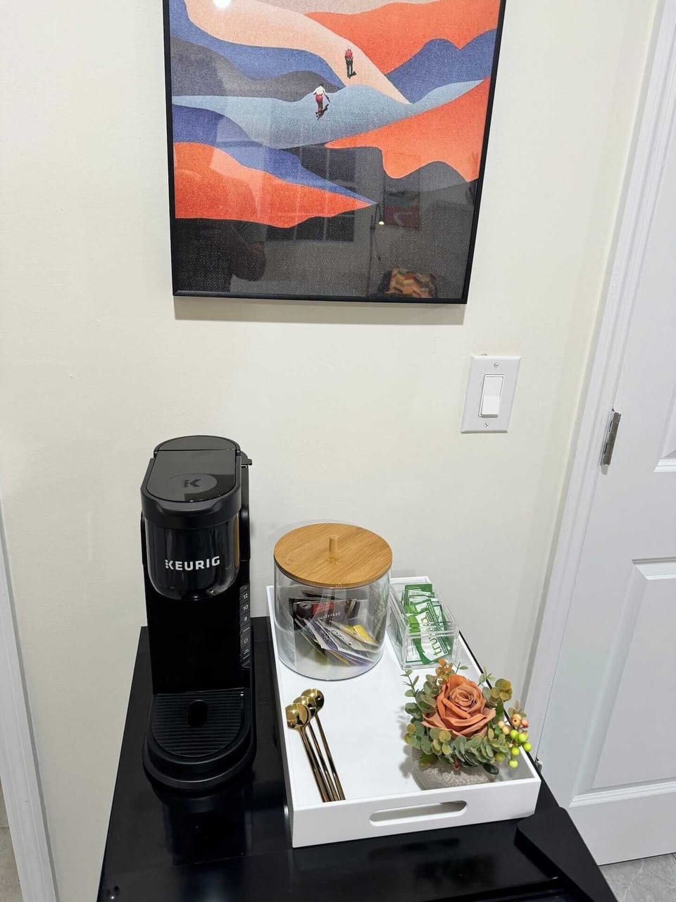 Coffee station with Keurig, tea selection, sugar, and a touch of floral decor.