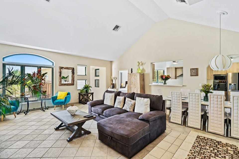 Step into this inviting living room featuring a plush, sectional sofa - Bright and airy, the space is accentuated by windows that let in plenty of natural light - The adjoining dining area seamlessly connects, making it easy to enjoy meals together