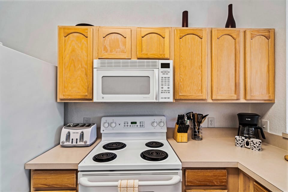Functional kitchen corner with essential appliances: microwave, stove, and toaster - Practical countertop space for meal preparation and cooking - Wooden cabinets provide storage, complemented by a convenient coffee maker for your morning brew