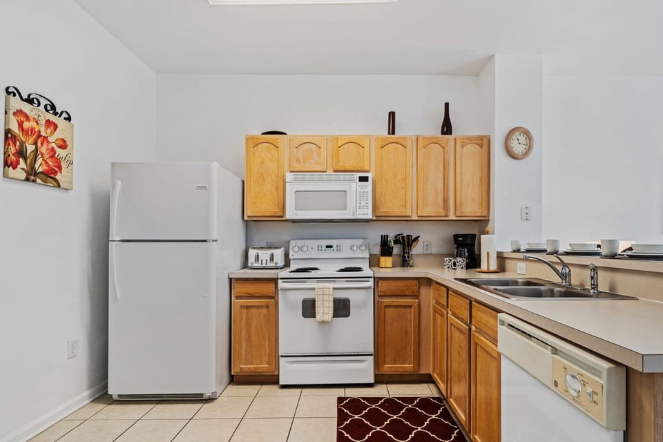Well-appointed kitchen featuring essential appliances - Sleek wooden cabinets and countertops provide both style and functionality - Decorative touches and practical layout enhance the cooking and dining experience