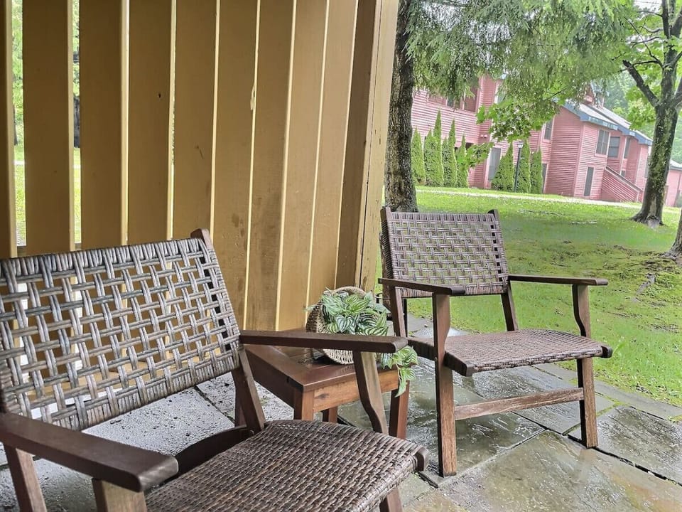 An outdoor patio with two woven chairs and a small side table.