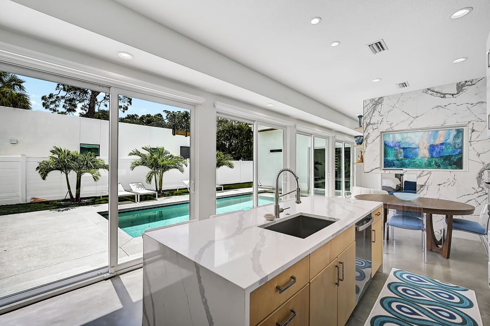 Sliding glass doors run the length of the living area, merging the chic indoor space, complete with a Smart TV and marble accent wall, with your tropical private pool and patio for the ultimate Florida experience.