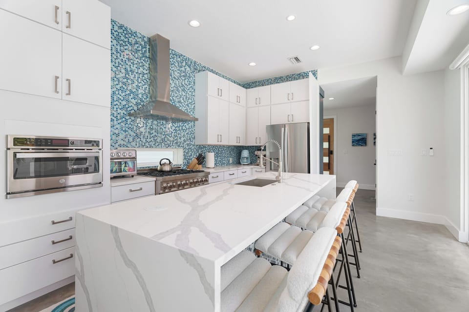 Your gourmet kitchen features stunning ocean-inspired mosaic tiles, a spacious marble island for casual meals, and top-of-the-line stainless steel appliances ready to inspire culinary adventures.
