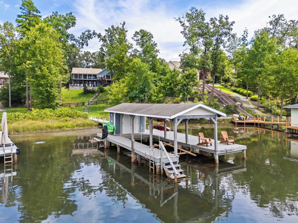 A charming waterfront dock with a covered boat slip, Adirondack chairs, and tranquil lake views, ideal for lakeside relaxation and activities.