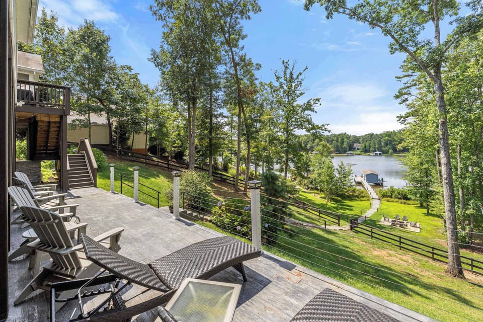 Spacious outdoor deck with lounge chairs overlooking a lush, tree-filled yard and serene lake views, offering a perfect spot for relaxation