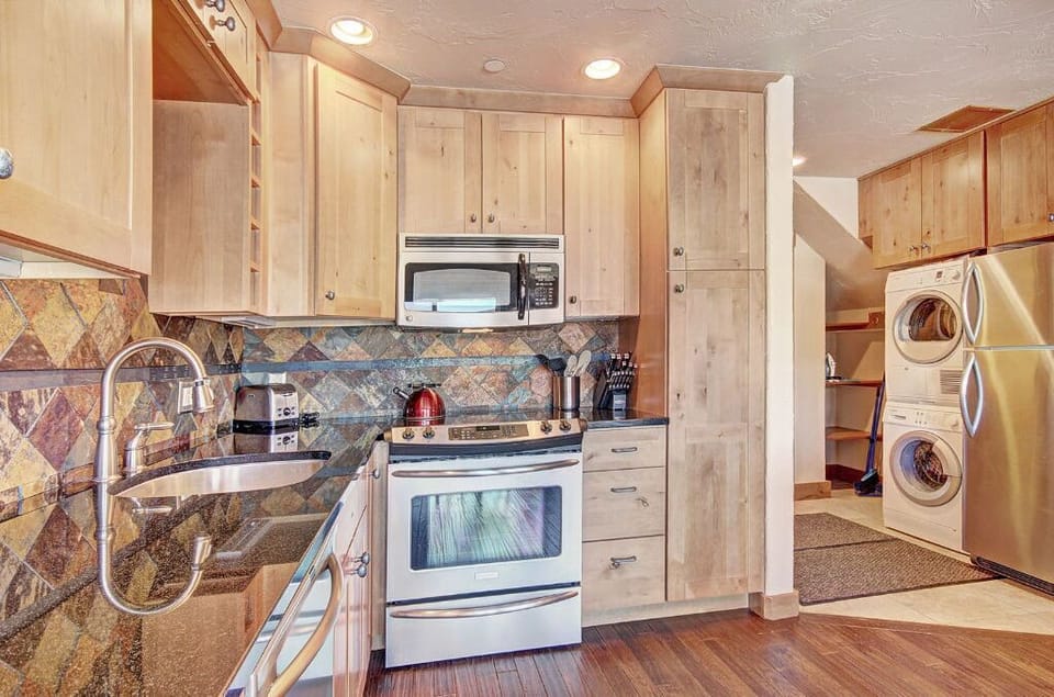 Prepare meals with ease in the fully equipped kitchen, boasting stainless steel appliances, wooden cabinetry, and a convenient layout.