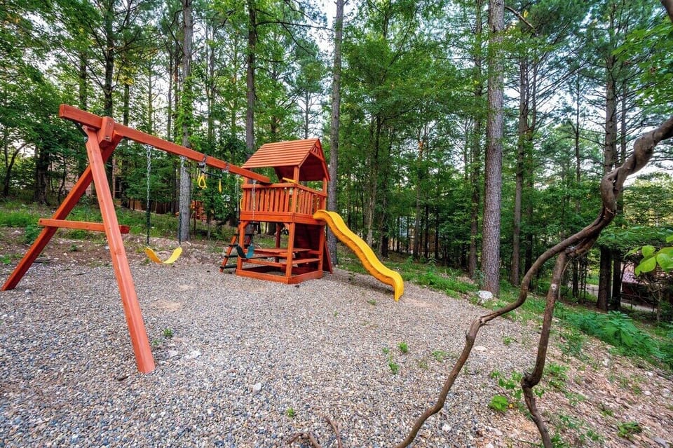 Outdoor playset with slide, swings, rock climbing wall, and treehouse