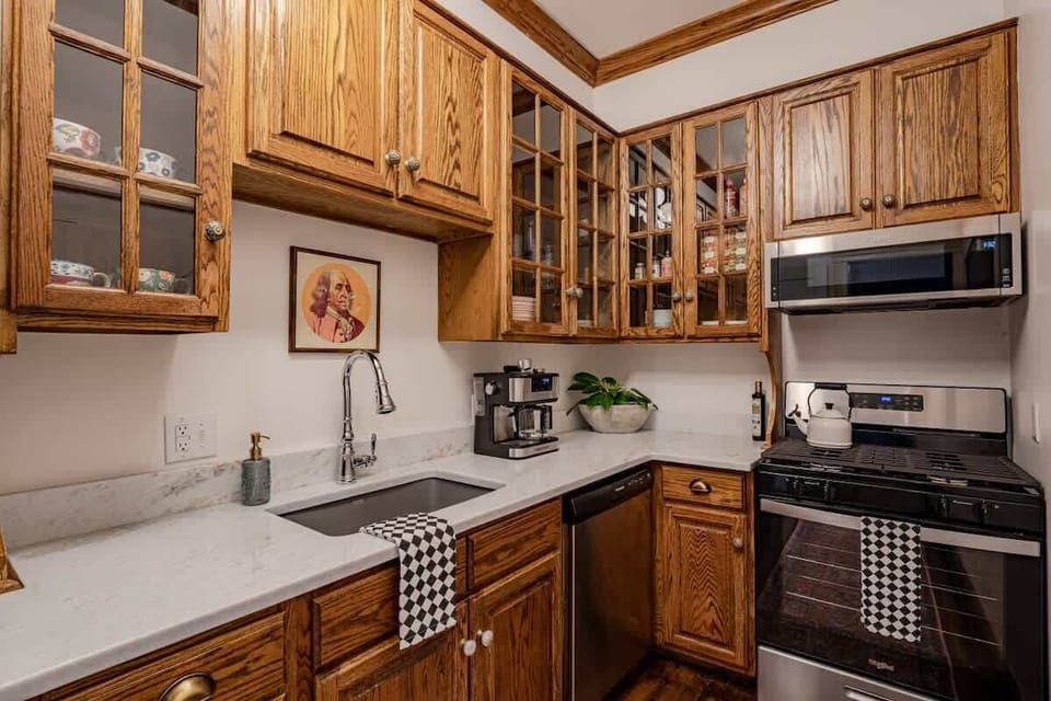 Classic kitchen w/ wood cabinets, tiled backsplash & bright window light while you cook